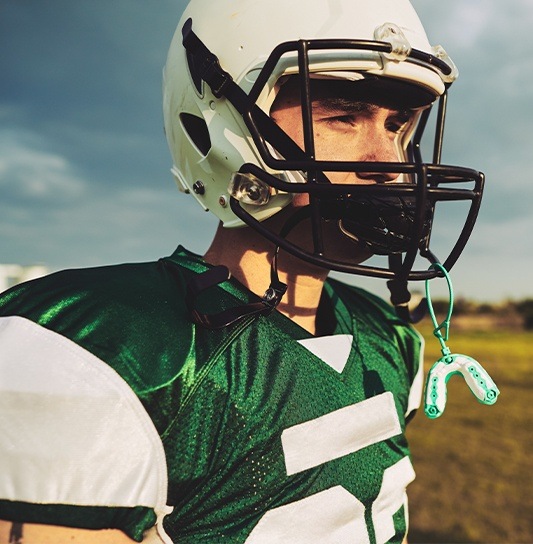 Teen boy with athletic mouthguard on helmet