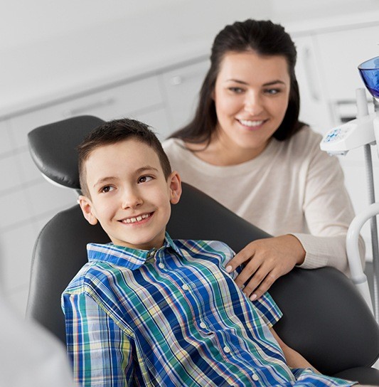 Young boy and his mother smiling together in dental office