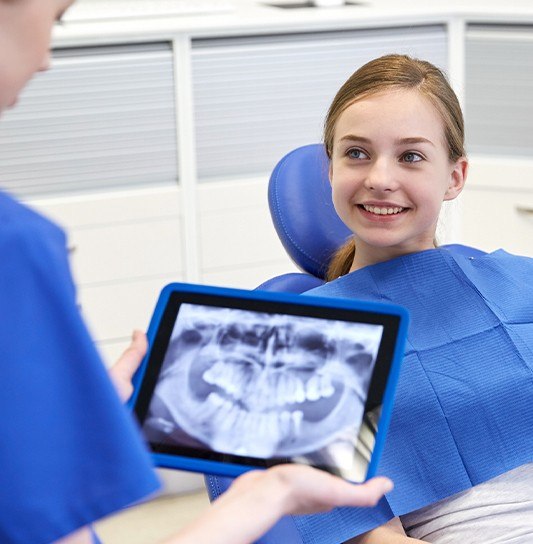 Dentist looking at child's digital x-rays on tablet computer