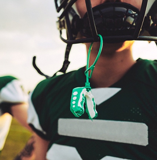 An up-close visual of a customized mouthguard hanging from a football helmet