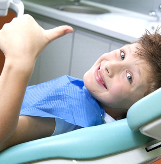 Young boy giving thumbs up after fluoride treatment in Cumming, FL
