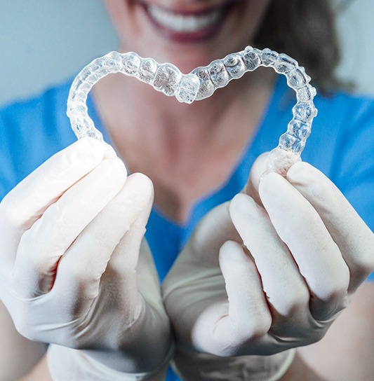 Dental team member holding Invisalign aligners in heart shape