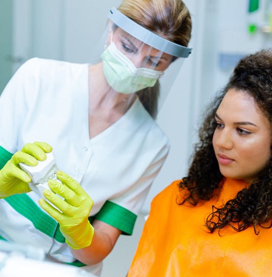 Teen girl looking at dental model, discussing Invisalign