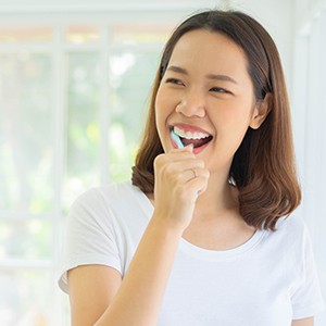 Girl smiling while brushing her teeth
