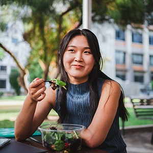 Girl smiling while eating lunch outside