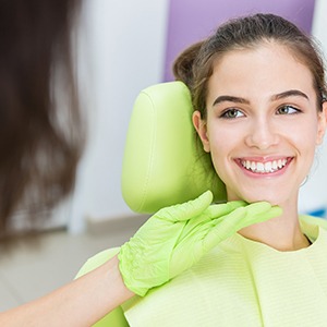 Dentist looking at smiling teen's teeth