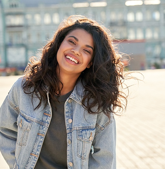 Teen in jean jacket smiling outside