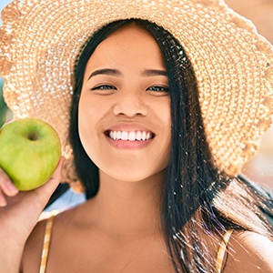 Teen girl smiling while holding green apple outside