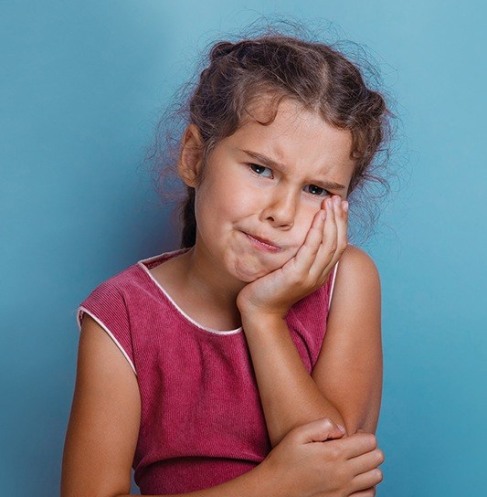 Child in need of pulp therapy holding cheek