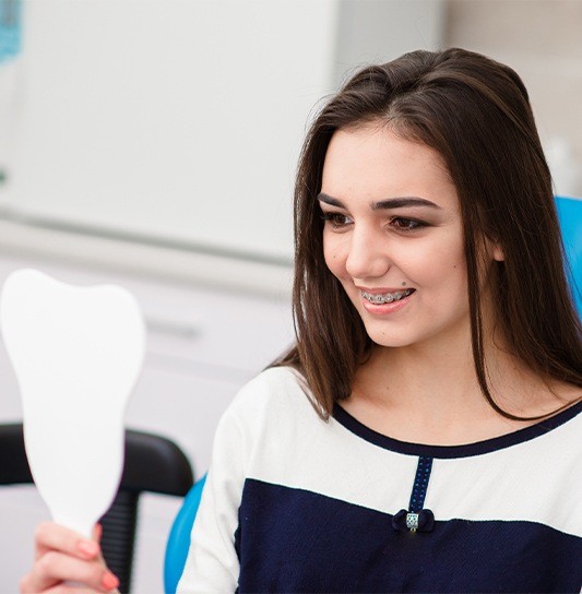 Teen girl with braces looking at her smile in mirror