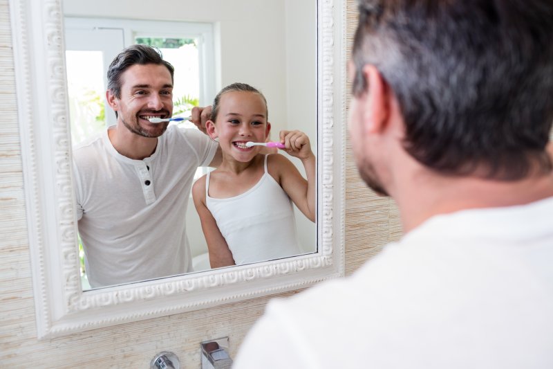 Father and daughter brushing their teeth