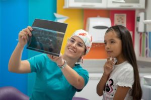 a pediatric dentist showing a child a copy of their dental X-ray