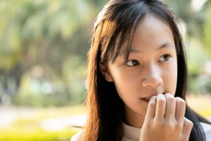 Nail-biting young girl looks worried