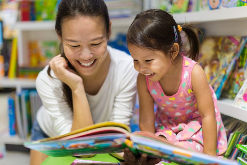 a mother and daughter having fun while reading books about dental visits