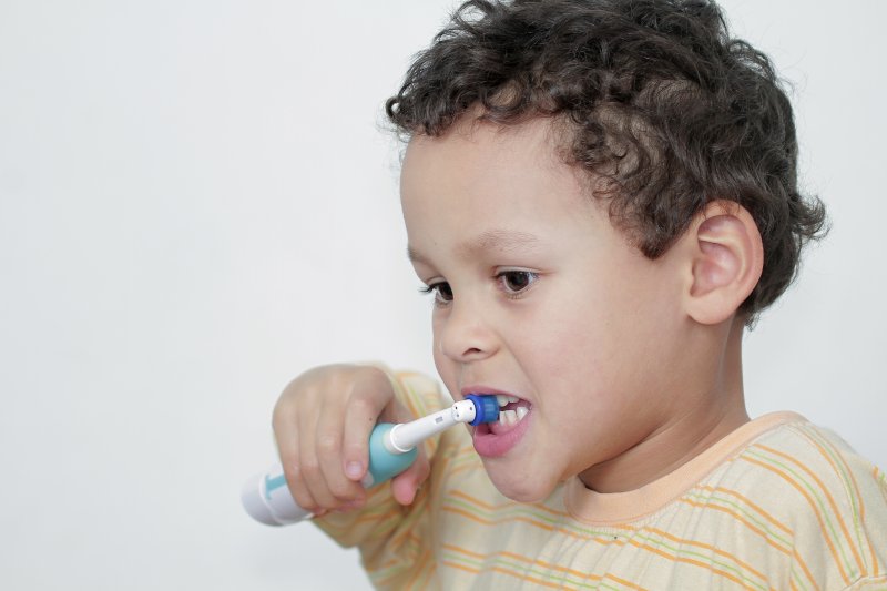 child using an electric toothbrush in Cumming