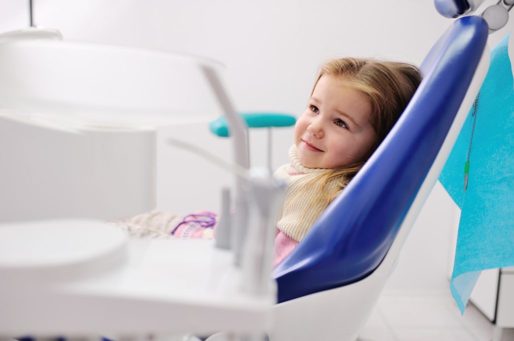 Child smiling while sitting in dental chair