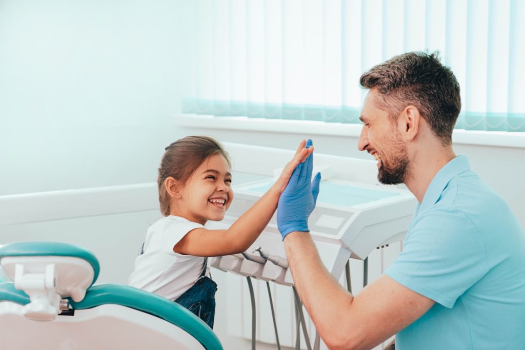 Child smiling while high-fiving dental hygienist