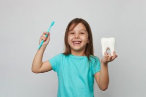 Happy child holding toothbrush and tooth model