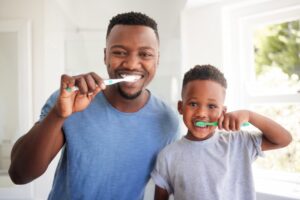 a father brushing his teeth with his son