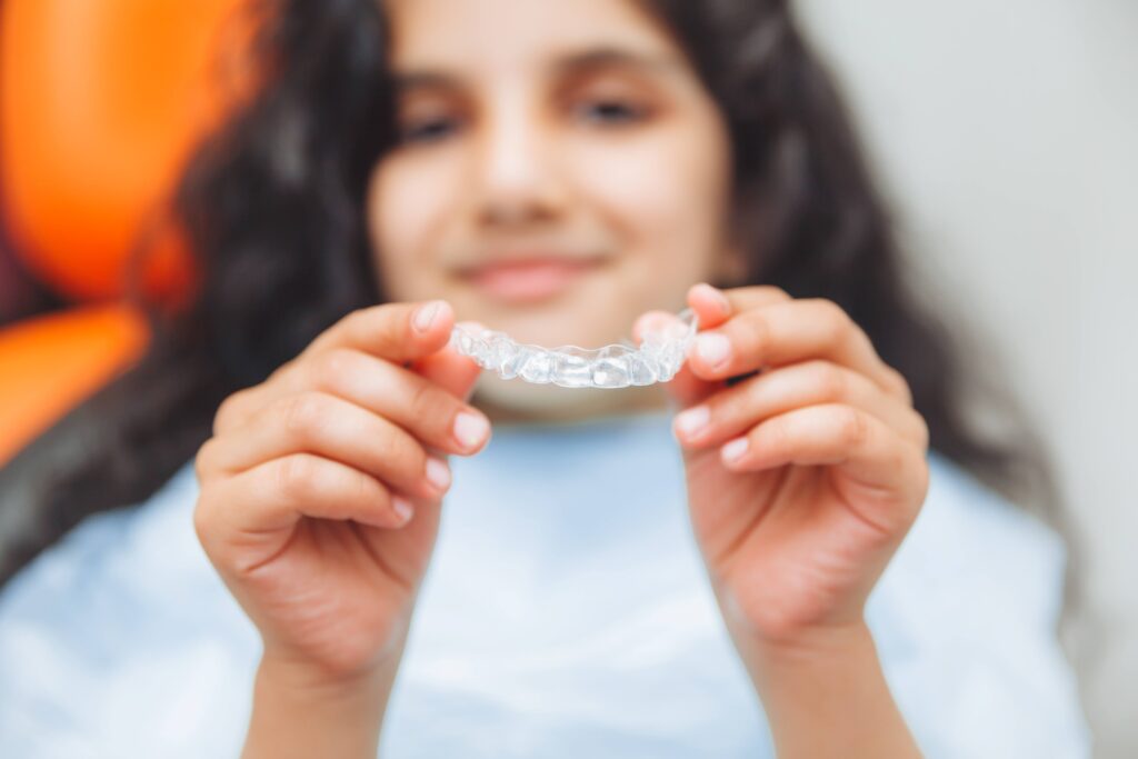 Teen holding Invisalign aligner