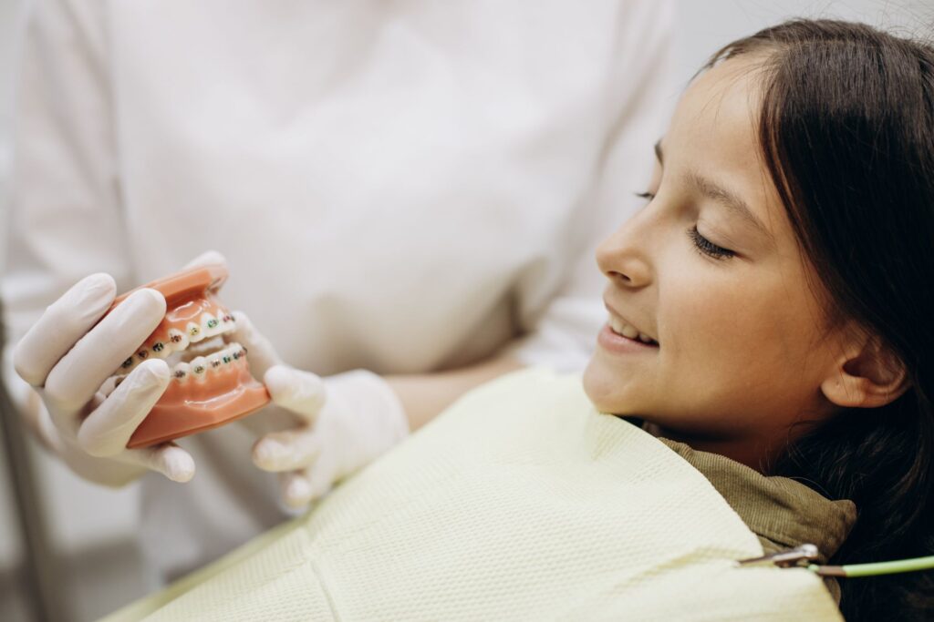 Dentist showing sample braces to girl in dental chair